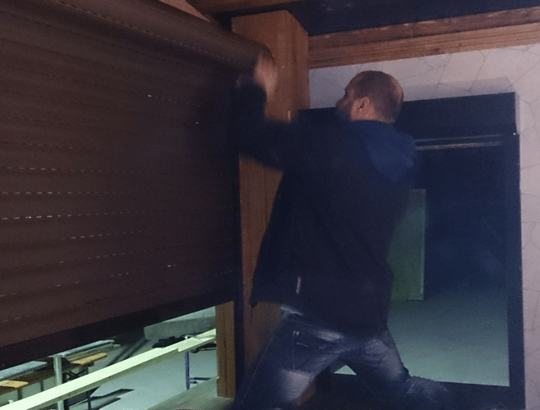 Eine Person schließt ein großes Rollladenbau-Garagentor aus Holz.